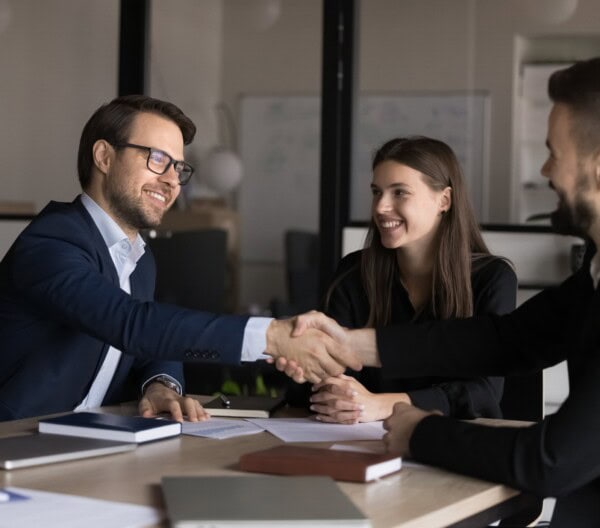 smiling male colleagues, shareholders shake hands close deal at meeting